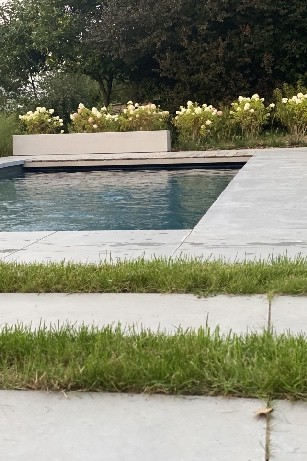 Aménagement d'une jardin avec piscine entourée de mégadalles en béton